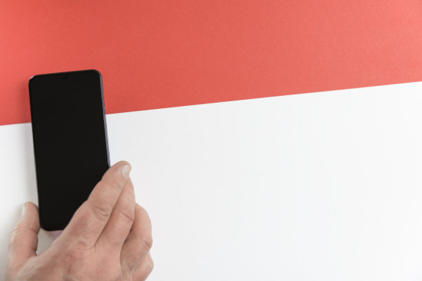 红色的线。手拿红白背景的智能手机。图片下载