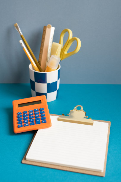 铅笔架，计算器，便签夹板在蓝色的桌子上。商业财务工作区图片下载