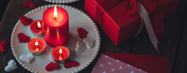 情人节庆祝活动。红色燃烧的蜡烛，爱心，礼品盒，明信片在黑暗的木制背景。节日快乐。餐桌装饰喜庆，气氛浪漫。横幅图片下载