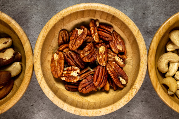 木板桌上放着烤核桃的木碗。俯视图，与其他干果的系列照片。图片下载