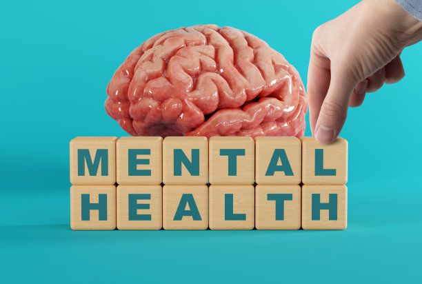 手触摸大脑背景上刻有“心理健康”字样的木块。图片下载