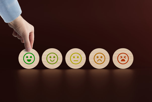 木制的圆盘上有从快乐到悲伤的面孔图标，一只手拿起一个有图标的圆盘。图片下载