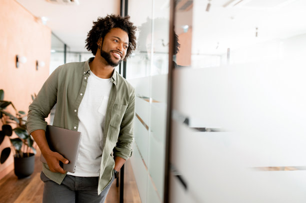 无忧无虑的非裔美国男性员工站在现代办公空间图片下载