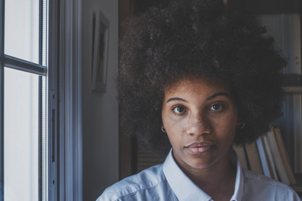 严肃的非裔美国女商人看着相机。女性高管的肖像，卷曲的发型，严肃的表情在办公室。公司办公室的黑人女士图片下载