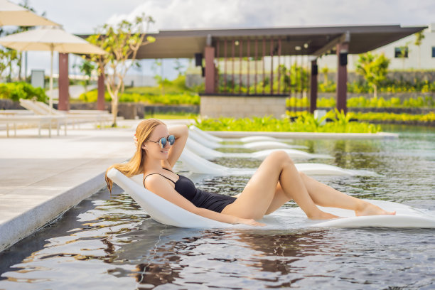 美丽的女孩在热带度假胜地的游泳池边放松图片下载
