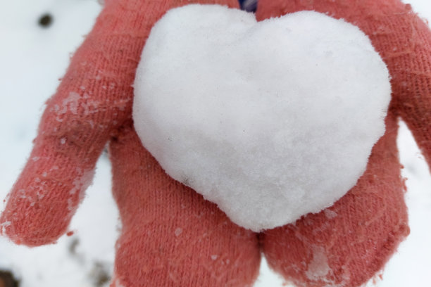 粉红色的婴儿手套握着一颗雪花般的心图片下载
