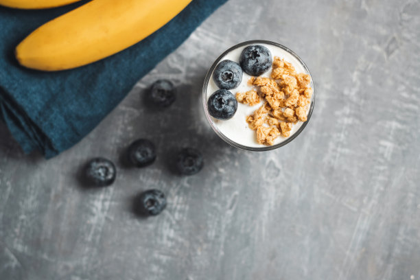格兰诺拉麦片麦片，白色酸奶，蓝莓和香蕉水果，在灰色背景的玻璃杯，俯视图图片下载