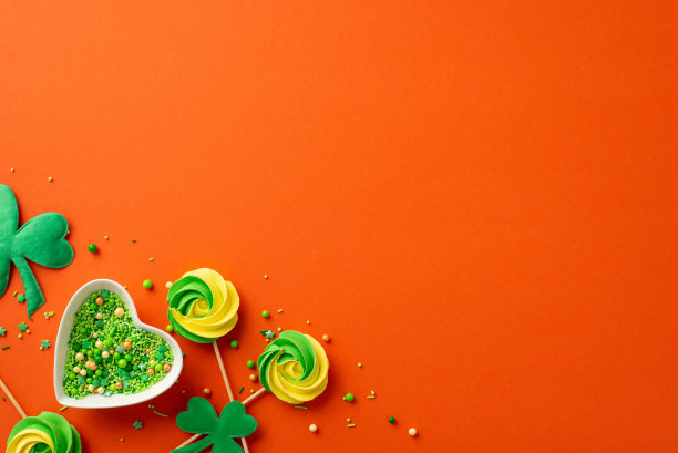 圣帕特里克节的概念。顶部视图照片的心形碟子洒蛋白糖和三叶草孤立的亮橙色背景与复制空间图片下载