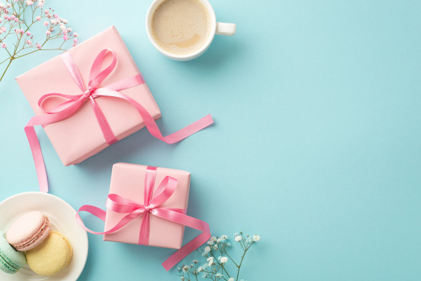 母亲节的概念。顶部视图照片粉红色礼盒与蝴蝶结茶托与马卡龙新鲜咖啡和吉卜草花在孤立的浅蓝色背景与复制空间图片下载