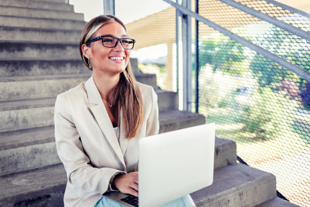 年轻女子在户外用笔记本电脑工作，在城市里。图片下载