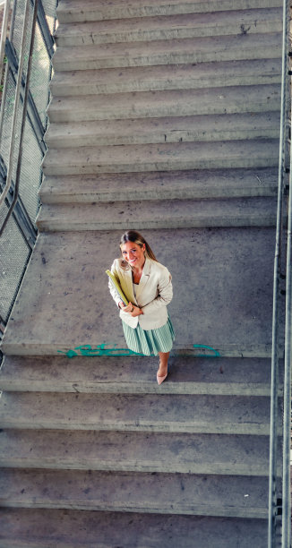 可爱的女商人走下楼梯的肖像，从上面看。图片下载