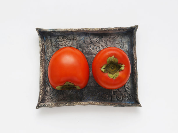 白色背景的蓝色陶瓷盘上的柿子水果，桌面视图。近距离照片的卡卡果与细节。图片下载