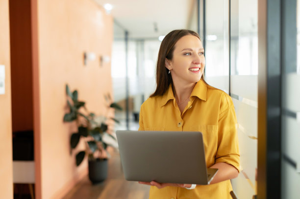 穿着休闲装的自信女性在现代办公室使用笔记本电脑图片下载
