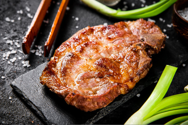 烤猪肉排放在石板上，配上葱和香料。图片下载