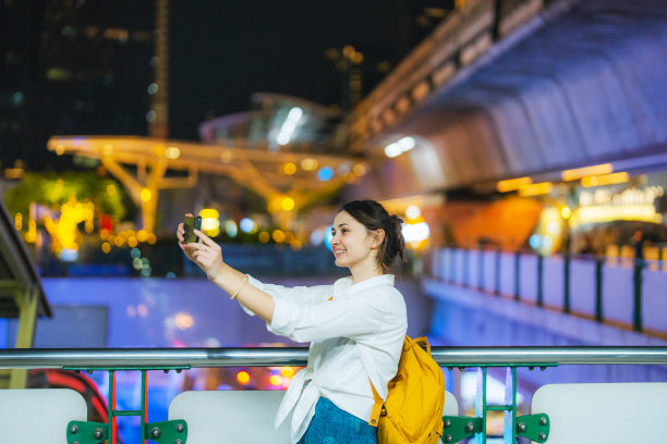 一位女士晚上在城市里走着的时候进行视频通话图片下载