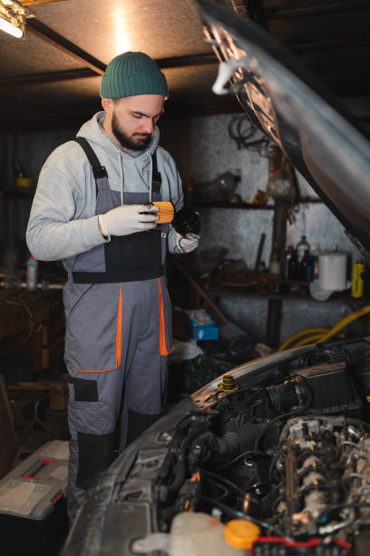 年轻的机械师正在他的车库里给一辆车更换机油和机油滤清器图片下载