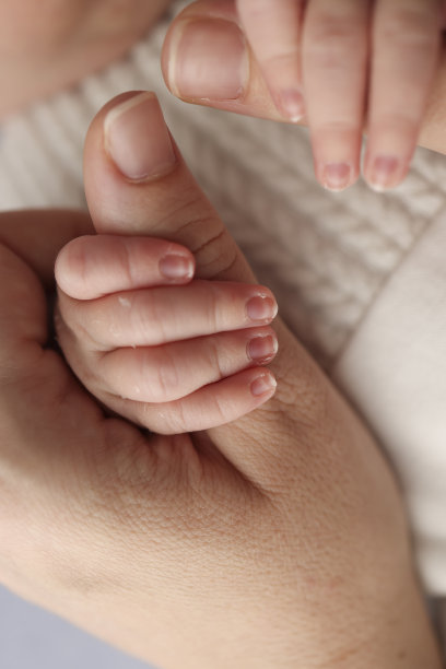 新生儿出生后会牢牢地抓住父母的手指。孩子的小手和爸爸妈妈的手掌特写。育儿、儿童保育和保健概念。专业微距照片。图片下载