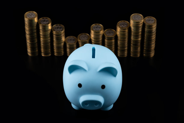 蓝色的存钱罐和堆放在黑色背景上的100哈萨克斯坦坚戈面额的硬币图片下载