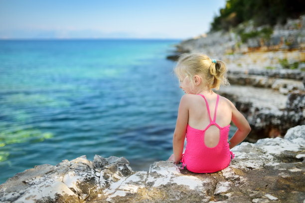 可爱的小女孩在Emplisi海滩玩得很开心，风景如画的石头海滩在一个僻静的海湾，清澈的海水适合浮潜。图片下载