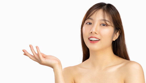 美容和水疗的概念。亚洲美女长发型干净新鲜的脸摆姿势手指向白色背景。图片下载