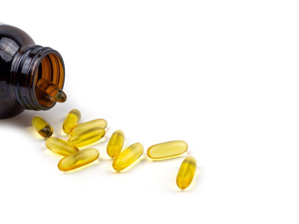 鱼油胶囊从瓶子里溢出来。软性明胶胶囊用于制药，含有油性药物和营养补充剂，顶部视图白色背景。图片下载