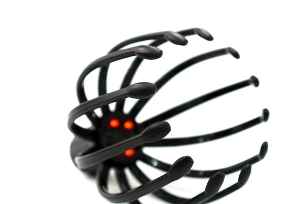 图为白色背景的便携式头部按摩装置，该装置由充电电池供电，用于放松按摩和促进头骨区域的血液循环。图片下载