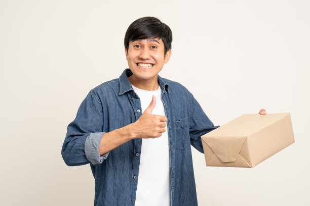 年轻兴奋的亚洲男子与许多包裹纸板站在孤立的白色背景。快乐的男子拿着许多包裹盒子从快递服务收到图片下载