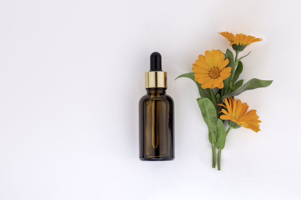 模型化妆品面部精华液棕色玻璃瓶与移液管在白色背景和金盏花，万寿菊。天然的化妆品。女性美的观念，空模板。平铺，复制空间。图片下载