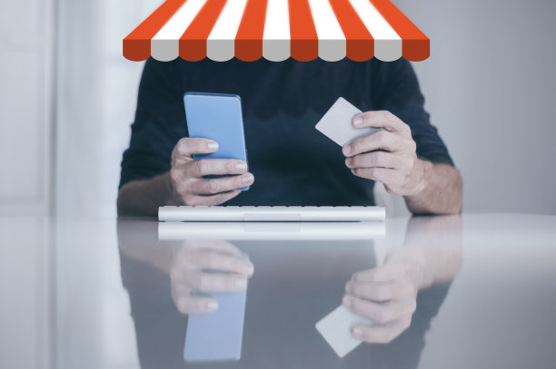 男人手里拿着智能手机和信用卡，在键盘上打字。网上购物电子商务概念图片下载