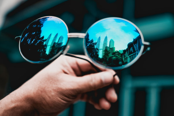 特写镜头的蓝色太阳镜在一个手反映马来西亚国家石油公司双塔在吉隆坡图片下载