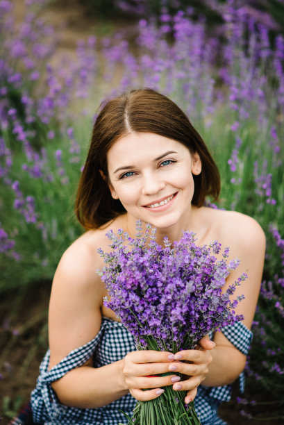 美丽的女孩在田野里捧着紫色的薰衣草花。女性收集薰衣草。薰衣草地里的女人。夏日，尽情享受花丛林间。视图。近距离图片下载