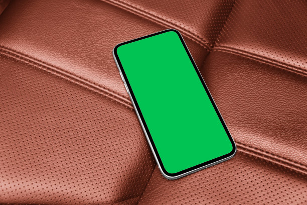 智能手机在汽车中用于导航或GPS。用智能手机开车。手机与隔离的绿色屏幕与色度键在红色穿孔皮革座椅。副本的空间。图片下载