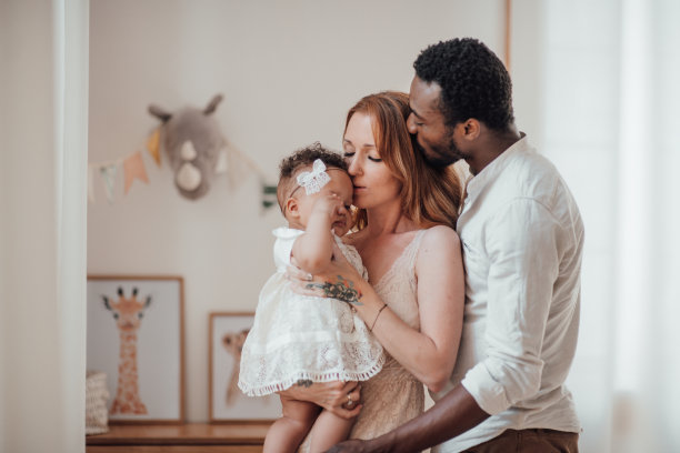 偷拍友好快乐的跨种族家庭与黝黑的婴儿一起在儿童房的肖像图片下载
