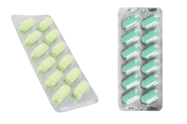 微距丸堆绿色片剂在吸塑包装隔离在白色背景。铝箔吸塑包装。药丸和毒品紧挨着。卫生保健。片的背景图片下载