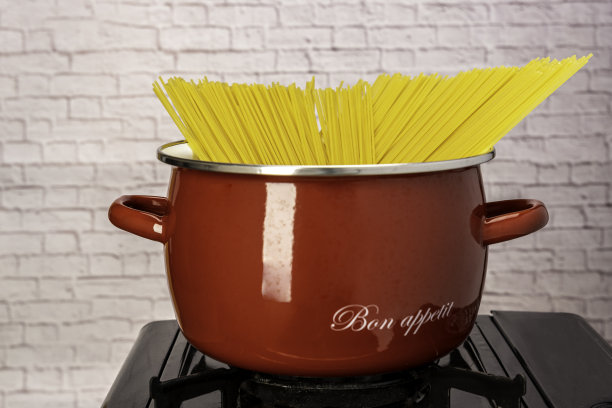 在煤气炉上用平底锅煮意大利面。自制的意大利式晚餐。红平底意大利面图片下载