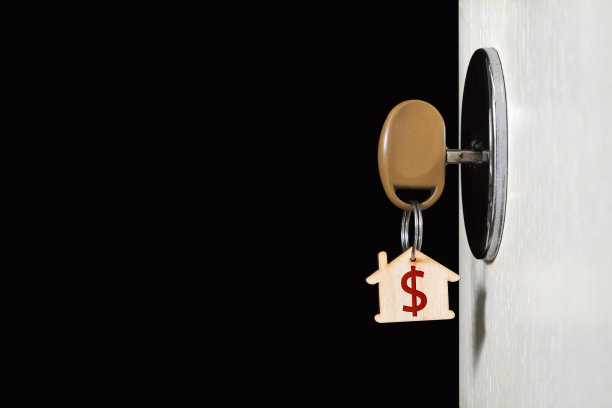 钥匙上有一个小饰品，在房子的门锁上，在黑暗的背景下，一扇敞开的门图片下载