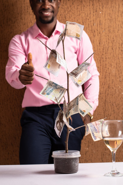 一名非洲男子在一棵摇钱树后面做着类似的手势图片下载