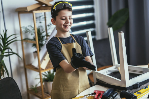 男孩木匠拿着木头在家里工作。家里的概念爱好。图片下载