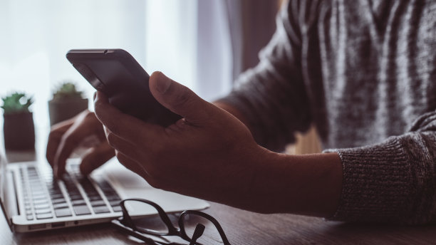 西班牙裔男子在家工作，看着他的智能手机图片下载