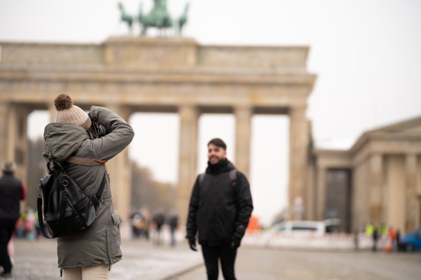 年轻的女摄影师在柏林勃兰登堡门为模特或游客拍照。图片下载