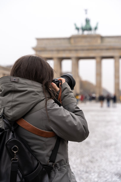 年轻的女摄影师正在拍摄柏林勃兰登堡门的照片。图片下载