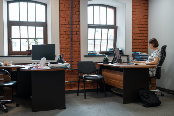 一个孕妇独自在半空的办公室工作。图片下载