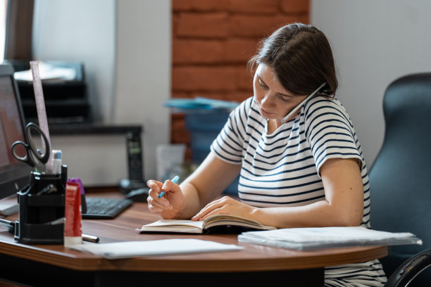 怀孕的女商人在办公室打电话。图片下载