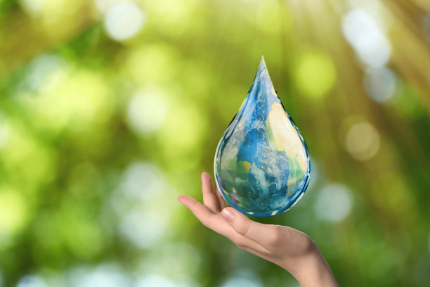 世界水日。女人拿着图标的下降与地球图像内模糊的绿色背景，特写图片下载