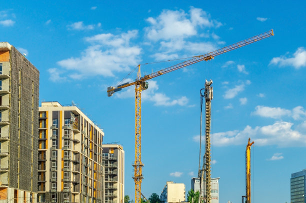 建筑起重机在天空背景上建造房屋。图片下载