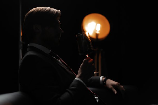 肖像的英俊优雅的男子与一杯酒在一个黑暗的房间图片下载
