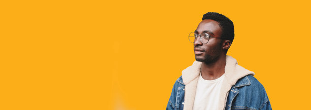 年轻的非洲男子戴眼镜的肖像孤立地看在黄色背景上，空白的复制空间为广告文字图片下载