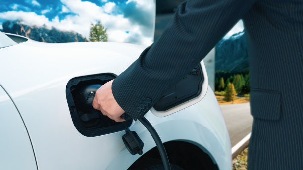 渐进式的旅行理念，人停电动汽车充电在森林。图片下载