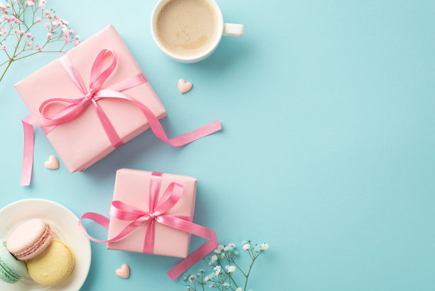 情人节的概念。顶部视图照片粉红色礼盒与蝴蝶结茶托与马卡龙咖啡杯小心脏和吉卜草花在孤立的粉彩蓝色背景与复制空间图片下载
