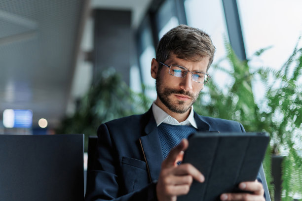 商务人士在出差期间使用电子平板电脑。图片下载